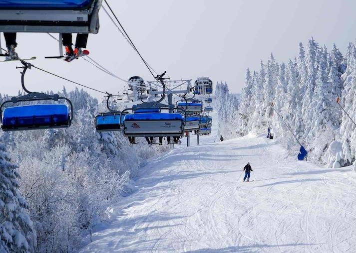 Skiier on a snowy mountain with ski lifts overhead